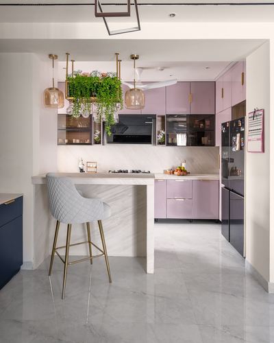 Pink glossy kitchen with marble island, quilted grey barstool, and hanging planters overhead