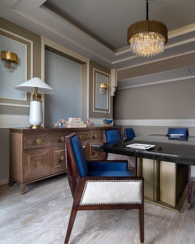 Study with carved wood sideboard, navy velvet chairs, black desk, and crystal chandelier