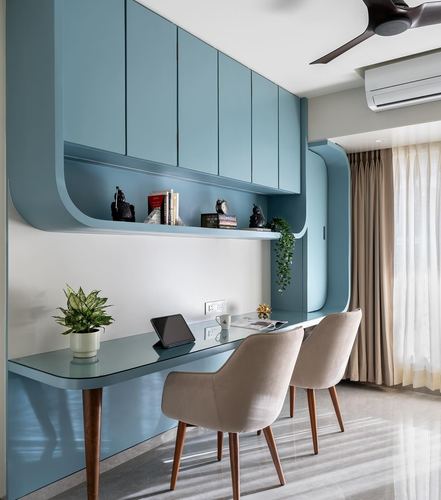 Blue curved study cabinetry with open shelf, glass desk and two beige chairs