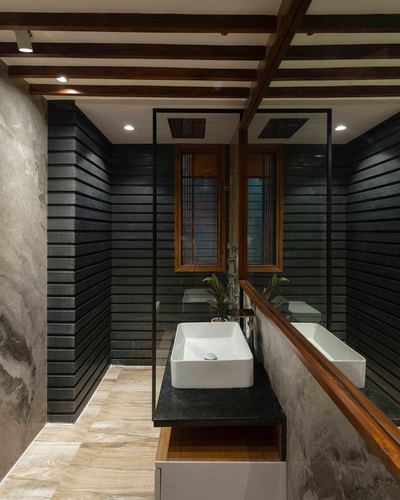 Bathroom with ribbed dark stone walls, wooden slat window, and rectangular vessel sink on black counter