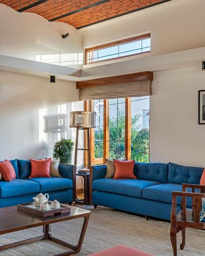 Living room with blue sectional sofas under a vaulted brick ceiling and tall wooden windows