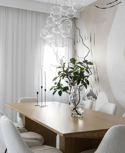 Minimalist dining table with boucle chairs, glass bubble chandelier and branch centerpiece