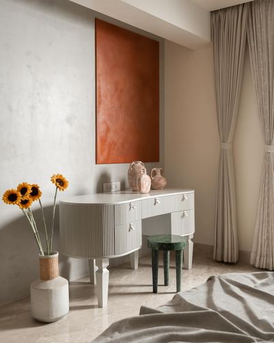 White fluted console with terracotta vases below an orange textured panel, green stool beside it