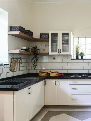 White L-shaped kitchen with subway tile backsplash, black countertops, and open wood shelving in corner