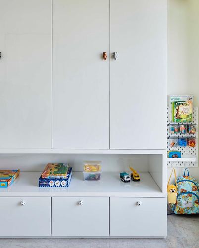 White children's storage cabinets with animal knobs, open shelf with toys, wall book rack