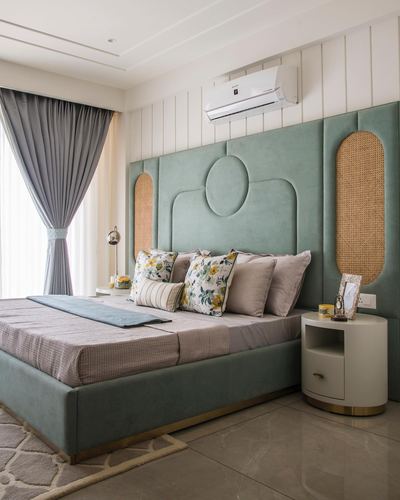 Sage green tufted headboard with cane inlay panels beside a round nightstand in a bedroom