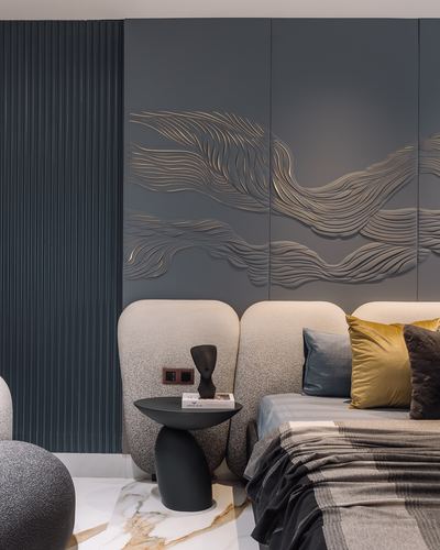 Bedroom with carved wave wall panel, boucle headboard, dark side table with sculpture on marble floor