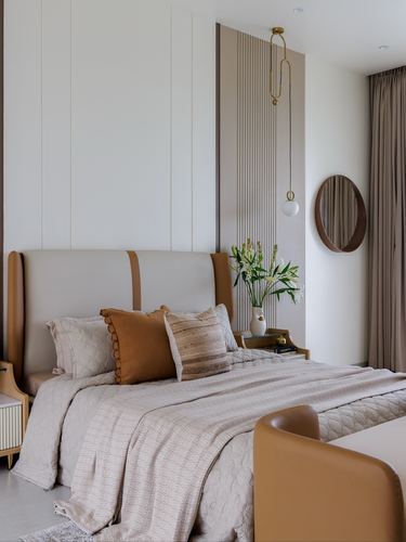Bedroom with tan leather headboard, fluted wall panel, pendant light and round mirror