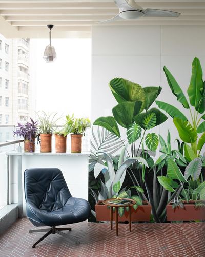 Balcony with terracotta herringbone floor, blue leather chair, and large tropical leaf mural wall