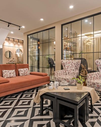 Living room with terracotta sofa, floral chairs and black-and-white geometric floor behind glass partitions