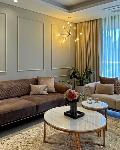 Living room with brown velvet sofa, round marble coffee tables, and gold sputnik chandelier