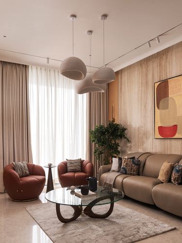 Living room with terracotta leather chairs, taupe sofa, sculptural glass coffee table and textured stone wall