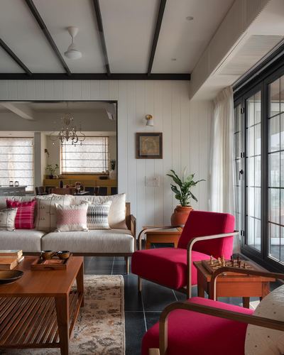 Living room with cream sofa, red armchairs, wooden chess table and black beamed ceiling