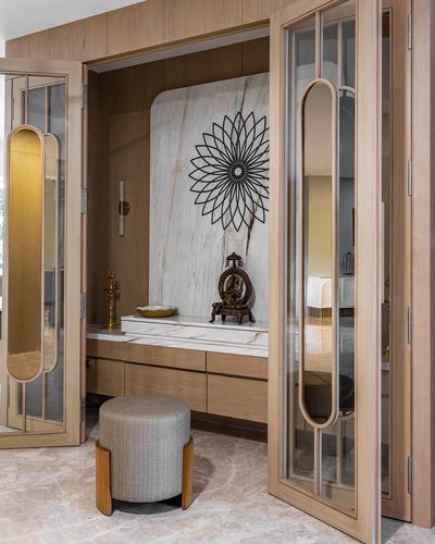 Wood-framed mirrored doors open to a marble pooja niche with a brass idol and metal sunburst sculpture
