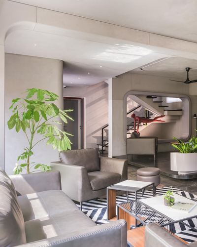 Living room with grey leather armchairs, zigzag rug, and an arched mirrored opening revealing a staircase.