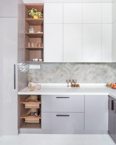 Modern L-shaped kitchen with white cabinetry, wood open shelving and herringbone tile backsplash