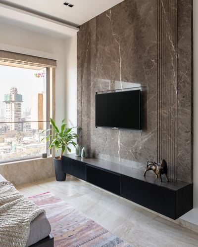 Bedroom with marble-look feature wall, mounted TV, black floating cabinet, and city view window