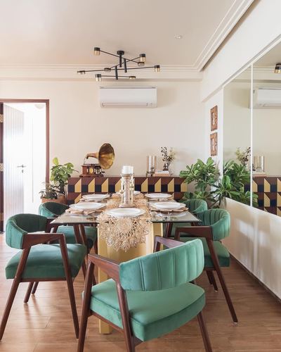 Dining room with glass-top table, green velvet chairs, gramophone decor, and geometric tile wall