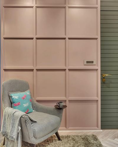Houndstooth armchair with dragonfly cushion against a pink paneled wall beside a green door