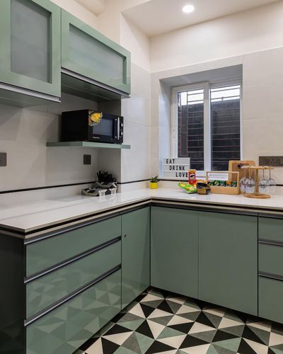 L-shaped sage green kitchen with white countertop and geometric patterned floor tile