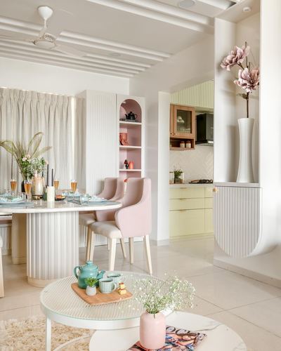 Pastel dining area with pink upholstered chairs opening into a mint-green kitchen beyond