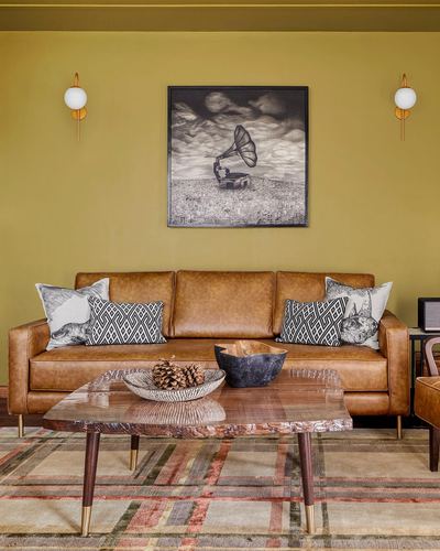 Mustard living room with tan leather sofa, framed gramophone art, and live-edge wood coffee table