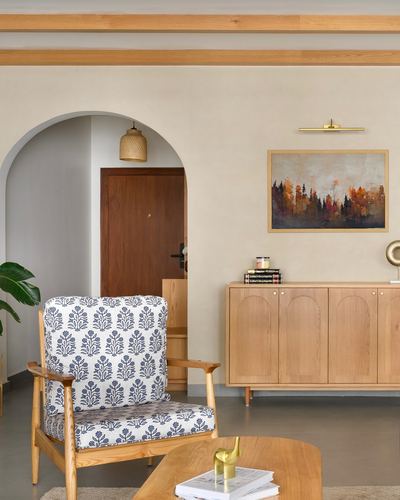 Living room with arched doorway, patterned armchair, wooden sideboard, and landscape painting