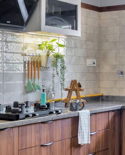 Kitchen counter with gas stove, wood cabinetry, granite counter, hanging plant and utensils