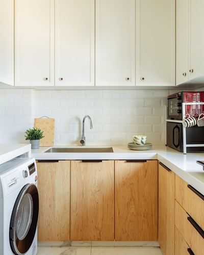 L-shaped kitchen with white upper cabinets, wood lower cabinets, subway tile backsplash, and washing machine