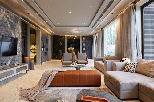 Open-plan living room with grey sectional sofa, orange leather ottoman, and marble tv wall