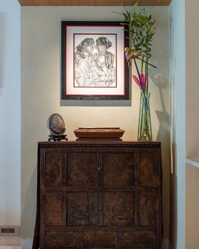 Antique carved wooden cabinet with vase, box and stone piece under a framed line drawing