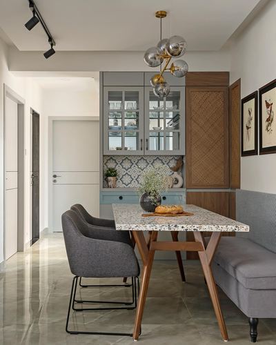 Dining nook with terrazzo table, cane cabinet, patterned tile backsplash and sphere pendant light