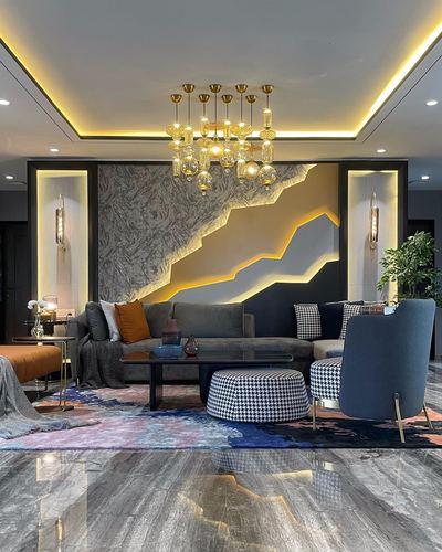 Living room with backlit stone accent wall, gold chandelier, and houndstooth ottoman on patterned rug