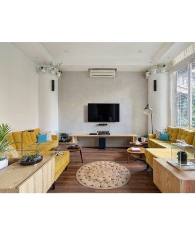 Symmetrical living room with mustard sofas facing a tv wall flanked by rounded columns