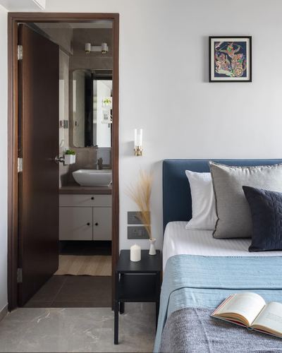 Bedroom with blue upholstered headboard beside open door to ensuite bathroom