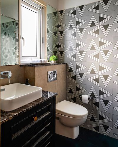 Bathroom with black-and-white triangle patterned tile wall, dark stone vanity, and wall-hung toilet