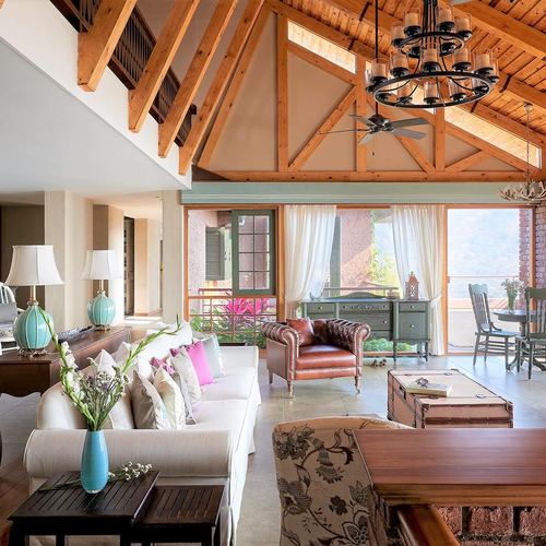 Farmhouse living room with vaulted timber truss ceiling, leather armchair, and view to valley through French doors
