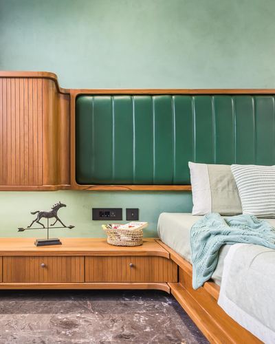 Bedside nook with tambour wood cabinet, green channel-tufted headboard, and horse sculpture on marble floor