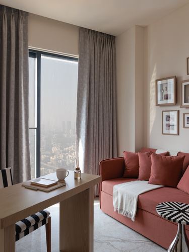Terracotta sofa by floor-to-ceiling window with city view and gallery wall, Mumbai apartment