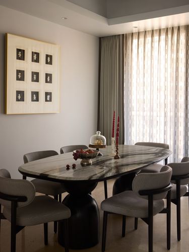 Oval marble dining table with striped grey chairs beneath layered sheer curtains and a grid artwork