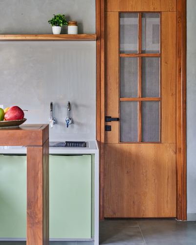 Kitchen corner with wood-framed glazed door, wall-mounted taps, and sage green cabinetry