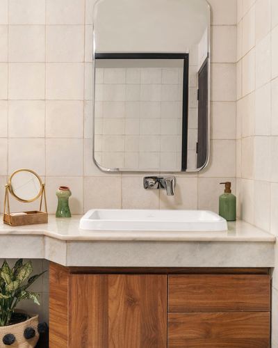 Bathroom vanity with zellige tile wall, stone countertop, wood cabinetry and wall-mounted faucet