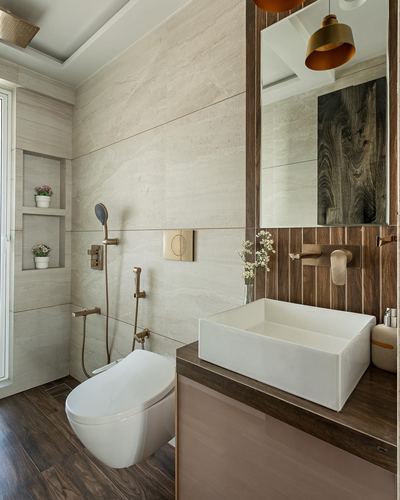 Bathroom with wood-panelled vanity wall, rectangular vessel sink, and stone-tiled shower area with brass fittings.