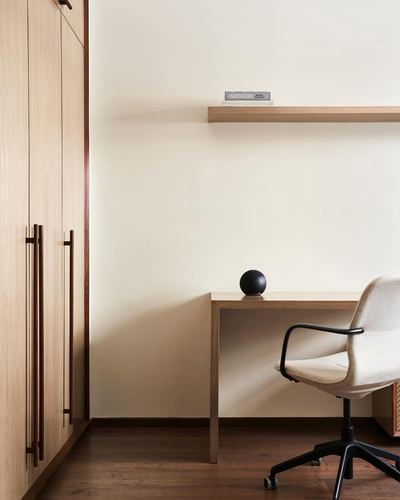 Minimalist study corner with wood wardrobe, floating shelf, desk and cream office chair
