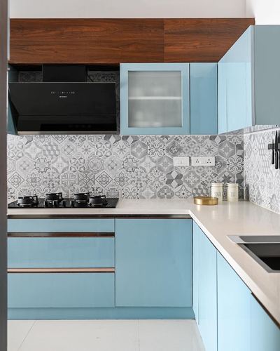 L-shaped kitchen with sky-blue glossy cabinets, patterned grey tile backsplash and wood-toned upper unit