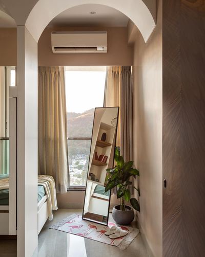 Arched bedroom nook with window, leaning mirror, shelf, plant and flamingo-print rug
