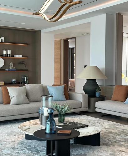 Modern living room with grey sofas, round marble coffee table, and sculptural gold pendant light