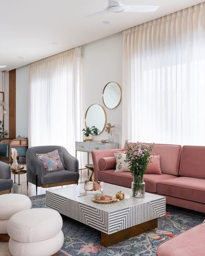 Living room with pink velvet sofa, grey armchair, striped coffee table and sheer curtains
