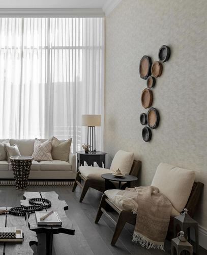 Living room with sheer curtains, wooden armchairs, cowhide table, and disc wall art