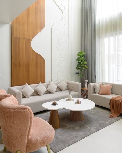 Living room with beige sofas, blush boucle chairs, and sculptural wood-and-plaster feature wall